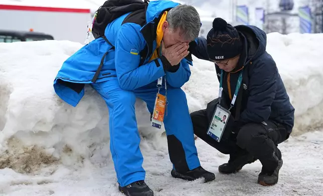 Mykhailo Heraskevych, father of Ukrainian skeleton athlete Vladyslav Heraskevych, reacts as he sits next to the start house of the sliding center at the 2026 Winter Olympics, in Cortina d'Ampezzo, Italy, Thursday, Feb. 12, 2026. (AP Photo/Fatima Shbair)