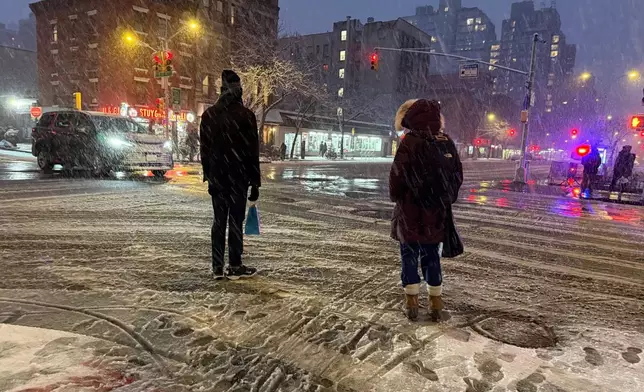 People wait to cross the corner of 20th Street and First Ave. during a snowstorm, Sunday, Feb. 22, 2026, in New York. (AP Photo/Pamela Hassell)