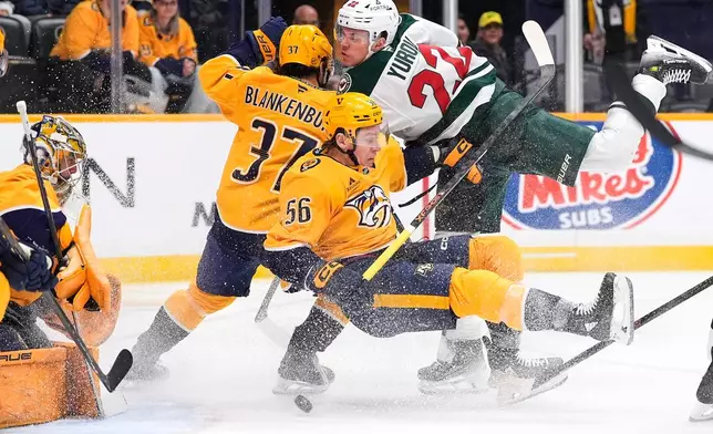 Minnesota Wild right wing Danila Yurov (22) tries to get the puck past Nashville Predators left wing Erik Haula (56), defenseman Nick Blankenburg (37) and goaltender Juuse Saros, left, during the first period of an NHL hockey game Wednesday, Feb. 4, 2026, in Nashville, Tenn. (AP Photo/George Walker IV)