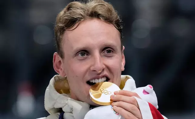 Sander Eitrem of Norway bites his gold medal on the podium after the men's 5,000 meters speedskating race at the 2026 Winter Olympics, in Milan, Italy, Sunday, Feb. 8, 2026. (AP Photo/Luca Bruno)