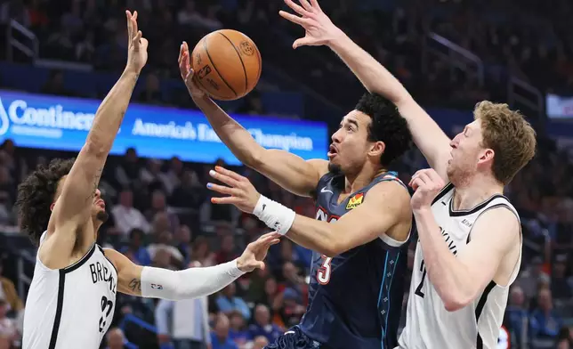Oklahoma City Thunder guard Jared McCain (3) looks to score between Brooklyn Nets forwards Jalen Wilson, left, and Danny Wolf, right, during the second half of an NBA basketball game Friday, Feb. 20, 2026, in Oklahoma City. (AP Photo/Nate Billings)