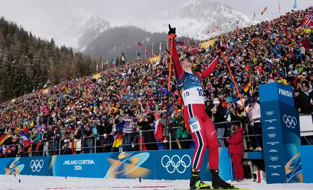 Johannes Dale-Skjevdal, of Norway, crosses the finish line to win gold in the men's 15-kilometer mass start biathlon race at the 2026 Winter Olympics in Anterselva, Italy, Friday, Feb. 20, 2026. (AP Photo/David J. Phillip)