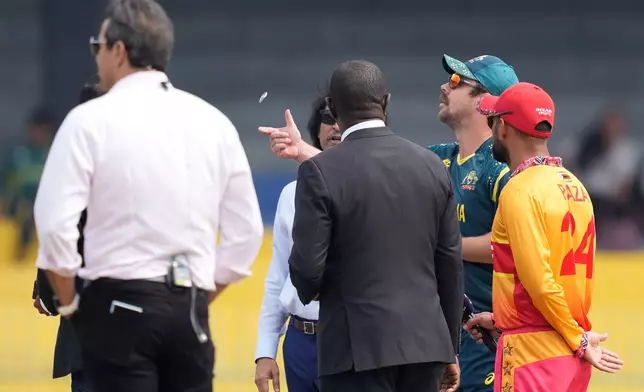 Australia's captain Travis Head, second right, toss the coin as Zimbabwe's captain Sikandar Raza, right, watch it before the starts of the T20 World Cup cricket match between Australia and Zimbabwe in Colombo, Sri Lanka, Friday, Feb. 13, 2026. (AP Photo/Eranga Jayawardena)