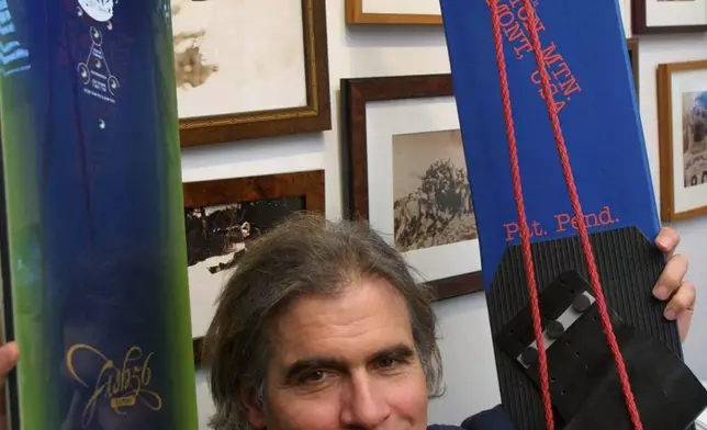 FILE - Jake Burton Carpenter, owner of Burton Snowboards, shows an early model, right, and one of the newer snowboards, left, in his office in Burlington, Vt., March 8, 2002. (AP Photo/Alden Pellett, File)