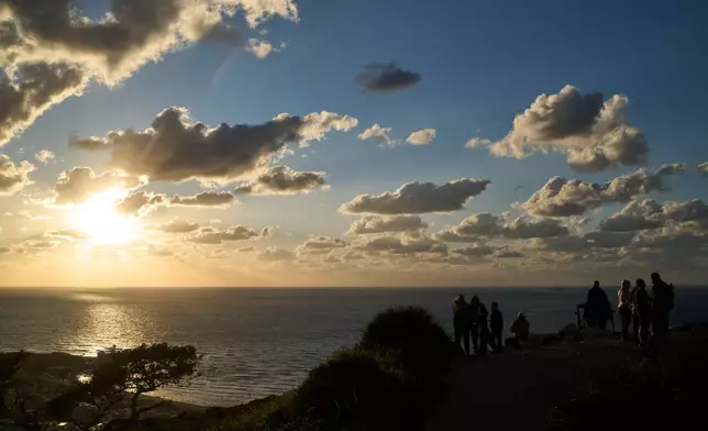 People gather at a lookout to look for the possible arrival of the US Navy's aircraft carrier USS Gerald R. Ford in the Mediterranean Sea near the coast of Haifa, northern Israel, Friday, Feb. 27, 2026. (AP Photo/Leo Correa)