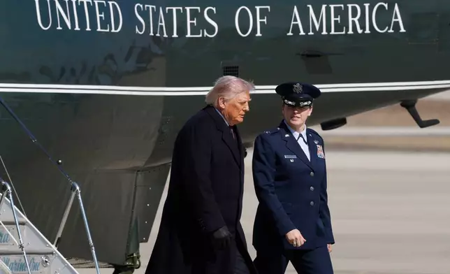 President Donald Trump, left, is greeted by Air Force 89th Air Wing Deputy Commander Melissa Dombrock, right, after exiting Marine One before boarding Air Force One, Friday, Feb. 27, 2025, at Joint Base Andrews, Md. (AP Photo/Luis M. Alvarez)