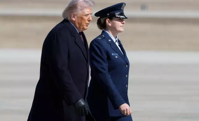 President Donald Trump, left, is escorted by Air Force 89th Air Wing Deputy Commander Melissa Dombrock, right, before boarding Air Force One, Friday, Feb. 27, 2025, at Joint Base Andrews, Md. (AP Photo/Luis M. Alvarez)