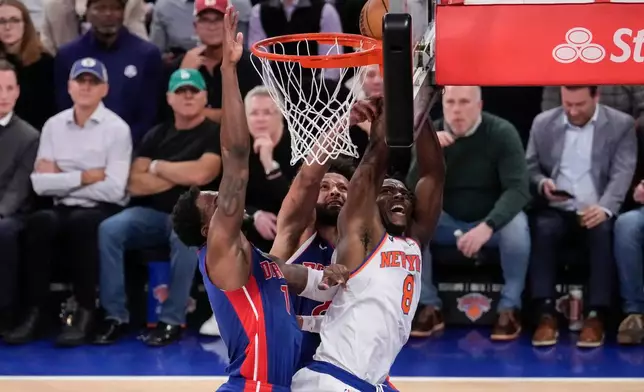 New York Knicks forward Og Anunoby (8) is blocked by Detroit Pistons guard Cade Cunningham (2) and Detroit Pistons forward Paul Reed (7) during the first half of an NBA basketball game, Thursday, Feb. 19, 2026, in New York. (AP Photo/Yuki Iwamura)