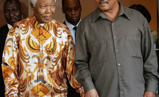 FILE - Former South African President Nelson Mandela, left, walks with the Rev. Jesse Jackson after their meeting in Johannesburg, South Africa, Oct. 26, 2005. (AP Photo/Themba Hadebe, File)