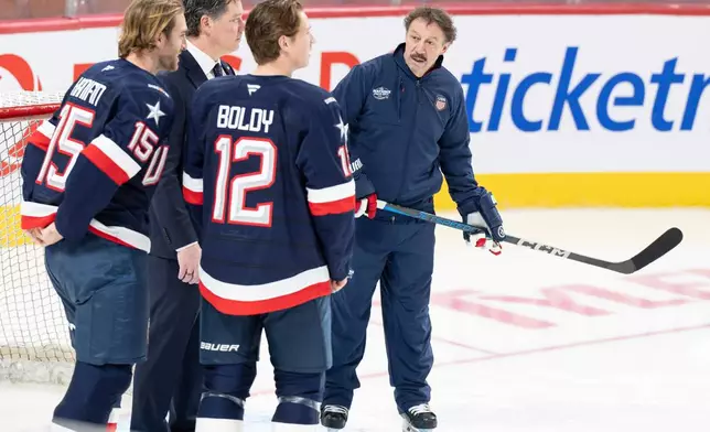 FILE - Guy Gaudreau, right, the father of the late Johnny and Matthew Gaudreau joins U.S.A. team players Noah Hanifin (15) and Matt Boldy (12) on the ice during 4 Nations Face-Off hockey practice in Montreal, Tuesday, Feb. 11, 2025. (Christinne Muschi/The Canadian Press via AP, File)