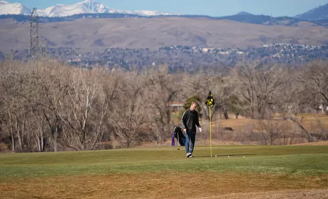 With little snow covering the mountain backdrop, a lone golfer putts out on a green on the Broken Tee Golf Course, Friday, Feb. 6, 2026, in Sheridan, Colo. (AP Photo/David Zalubowski)
