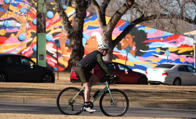 Taking advantage of daytime hgh temperatures in the 60s, a cyclist wheels through Washington Park, Friday, Feb. 6, 2026, in Denver. (AP Photo/David Zalubowski)