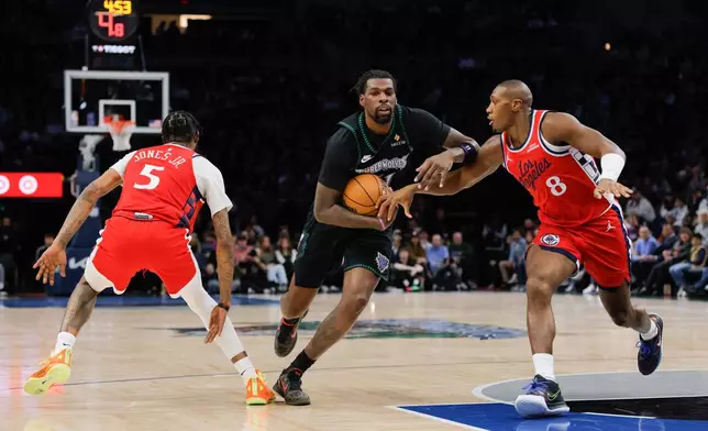 Minnesota Timberwolves center Naz Reid, center, drives to the basket while Los Angeles Clippers guard Kris Dunn (8) and forward Derrick Jones Jr. (5) defend during the first half of an NBA basketball game, Sunday, Feb. 8, 2026, in Minneapolis. (AP Photo/Bailey Hillesheim)