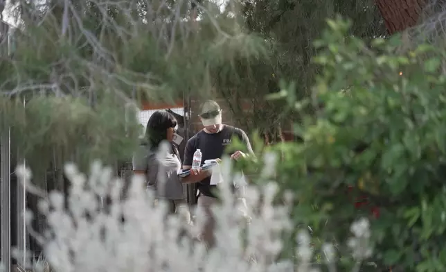 Investigators look over paperwork in the neighborhood where Annie Guthrie, whose mother Nancy Guthrie has been missing for more than a week, lives just outside Tucson, Ariz., on Tuesday, Feb. 10, 2026. (AP Photo/Ty ONeil)
