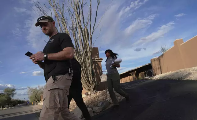 Law enforcement agents walk around the neighborhood where Annie Guthrie, whose mother Nancy Guthrie has been missing for more than a week, lives just outside Tucson, Ariz. (AP Photo/Ty ONeil)