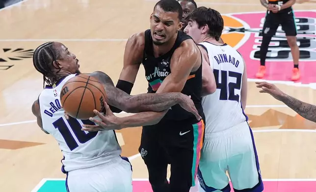 San Antonio Spurs forward Victor Wembanyama, center, is fouled by Sacramento Kings guard DeMar DeRozan (10) as he drives to the basket during the second half of an NBA basketball game in Austin, Texas, Saturday, Feb. 21, 2026. (AP Photo/Eric Gay)