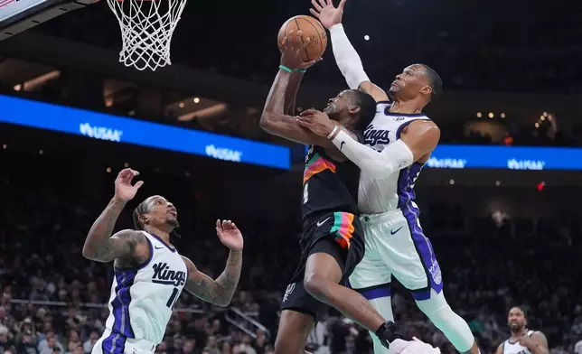San Antonio Spurs guard De'aaron Fox (4) is blocked by Sacramento Kings guard Russell Westbrook (18) as he drives to the basket during the second half of an NBA basketball game in Austin, Texas, Saturday, Feb. 21, 2026. (AP Photo/Eric Gay)