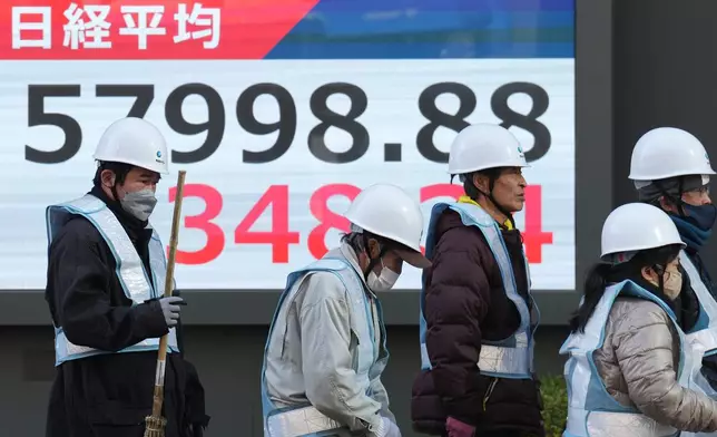 People walk in front of an electronic stock board showing Japan's Nikkei index at a securities firm Thursday, Feb. 12, 2026, in Tokyo. (AP Photo/Eugene Hoshiko)