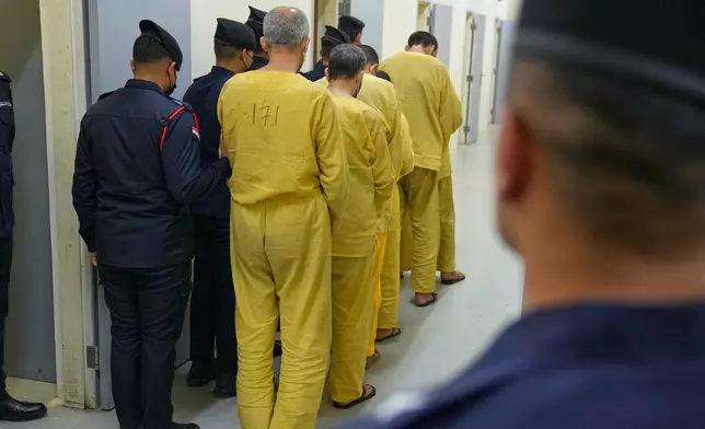 Iraqi security forces lead suspected Islamic State militants for questioning, after they were transferred from Syria to Iraq, at Al-Karkh Central Prison in Baghdad, Iraq, Thursday, Feb. 12, 2026. (AP Photo/Hadi Mizban)