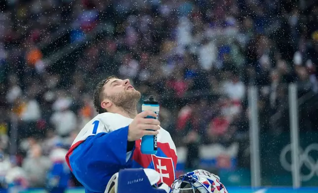 Slovakia's Samuel Hlavaj sprays water during a men's ice hockey quarterfinal game between Slovakia and Germany at the 2026 Winter Olympics, in Milan, Italy, Wednesday, Feb. 18, 2026. (AP Photo/Petr David Josek)