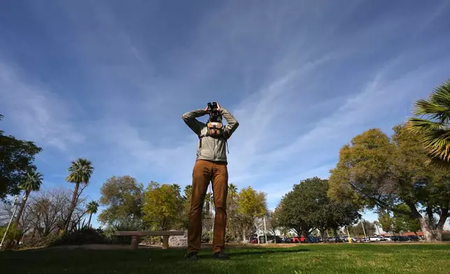 Robert Carter, of the Maricopa Bird Alliance, looks through binoculars for love birds in Encanto Park, Jan. 18, 2026, in Phoenix. (AP Photo/Ross D. Franklin)