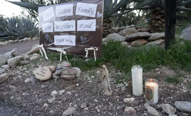 Lit candles next to a sign from neighbors supporting the Guthrie family outside of Nancy Guthrie’s house in the early morning hours of Sunday, Feb. 8, 2026 in Tucson, Ariz. (AP Photo/Ty ONeil)