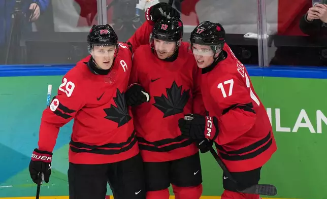 Canada's Sam Reinhart (13) celebrates with Nathan MacKinnon (29) and Macklin Celebrini (17) after Reinhart scored a goal against Finland during the second period of a men's ice hockey semifinal game at the 2026 Winter Olympics in Milan, Italy, Friday, Feb. 20, 2026. (AP Photo/Carolyn Kaster)