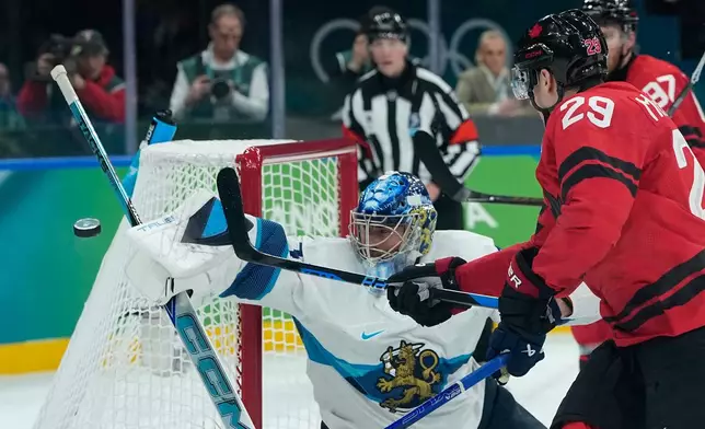 Finland's Juuse Saros (74) makes a save in front of Canada's Nathan MacKinnon (29) during a men's ice hockey semifinal game between Canada and Finland at the 2026 Winter Olympics, in Milan, Italy, Friday, Feb. 20, 2026. (AP Photo/Petr David Josek)