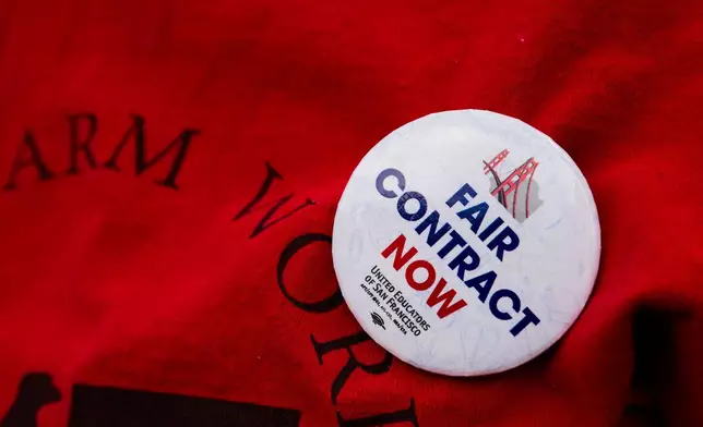 Denise Deleon, a kindergarten teacher at Gordon J. Lau Elementary School, wears a button stating "Fair Contract Now" as she protests with fellow teachers, students and parents in the SFUSD Teachers Strike outside of Chinatown's Gordon J. Lau Elementary School, in San Francisco, Wednesday, Feb. 11, 2026. (Yalonda M. James/San Francisco Chronicle via AP)