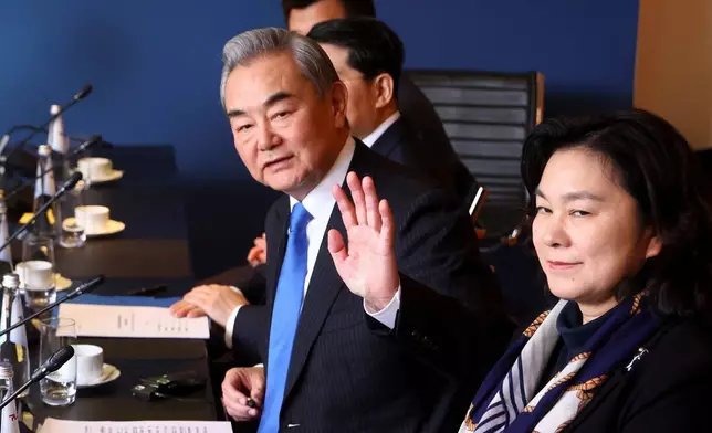 Chinese Foreign Minister Wang Yi gestures as he meets with German Chancellor Friedrich Merz at the Munich Security Conference in Munich, Germany, Saturday Feb. 14, 2026. (Thilo Schmuelgen/Pool Photo via AP)
