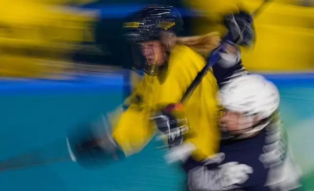 Sweden's Thea Johansson, left, challenges France's Clara Rozier during a preliminary round match of women's ice hockey between France and Sweden at the 2026 Winter Olympics, in Milan, Italy, Sunday, Feb. 8, 2026. (AP Photo/Petr David Josek)