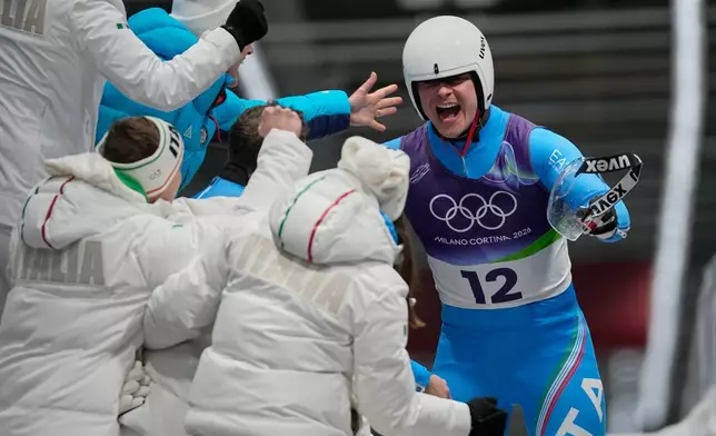 Italy's Dominik Fischnaller, right, celebrates winning the bronze medal as he arrives at the finish during a men's single luge run at the 2026 Winter Olympics, in Cortina d'Ampezzo, Italy, Sunday, Feb. 8, 2026. (AP Photo/Aijaz Rahi)