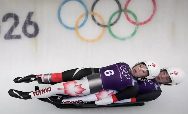 Canada's Beattie Podulsky, left, and Kailey Allan, right, slide down the track during a women's doubles luge training session at the 2026 Winter Olympics, in Cortina d'Ampezzo, Italy, Sunday, Feb. 8, 2026. (AP Photo/Aijaz Rahi)