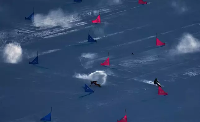 Switzerland's Ladina Caviezel, left, and compete Ukraine's Annamari Dancha during the women's snowboarding parallel giant slalom qualifications at the 2026 Winter Olympics, in Livigno, Italy, Sunday, Feb. 8, 2026. (AP Photo/Abbie Parr)