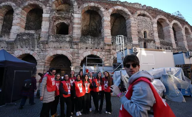 Volunteers stand close to the Arena ahead of the closing ceremony at the 2026 Winter Olympics, in Verona, Italy, Tuesday, Feb. 17, 2026. (AP Photo/Antonio Calanni)