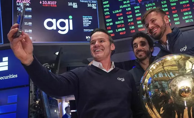 AGI Inc Founder, Executive Chairman &amp; CEO Marciano Testa, left, Governance Officer Lucas Aguiar, center, and Chief Client Officer Matheus Girardi take a selfie photo on the floor of the New York Stock Exchange after their company's IPO began trading, Wednesday, Feb. 11, 2026. (AP Photo/Richard Drew)