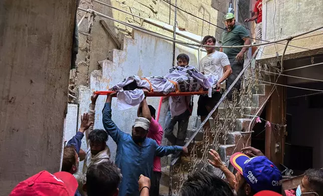 Rescue workers carry a body after recovering from the rubble following a gas explosion in an apartment building in Karachi, Pakistan, Thursday, Feb. 19, 2026. (AP Photo/Mohammad Farooq)