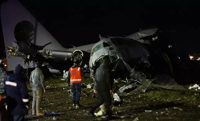 People walk on the scene where a plane crashed on a highway in El Alto, Bolivia, Friday, Feb. 27, 2026. (AP Photo/Juan Karita)