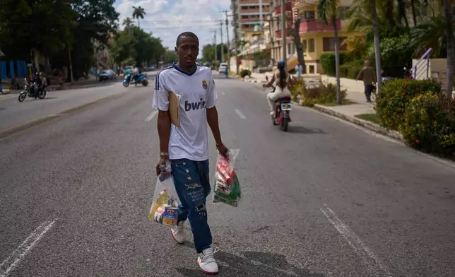 State-run bodega manager Roberto Roman carries bags of donated Mexican humanitarian assistance to be delivered to a family, in Havana, Cuba, Thursday, Feb. 19, 2026. (AP Photo/Ramon Espinosa)