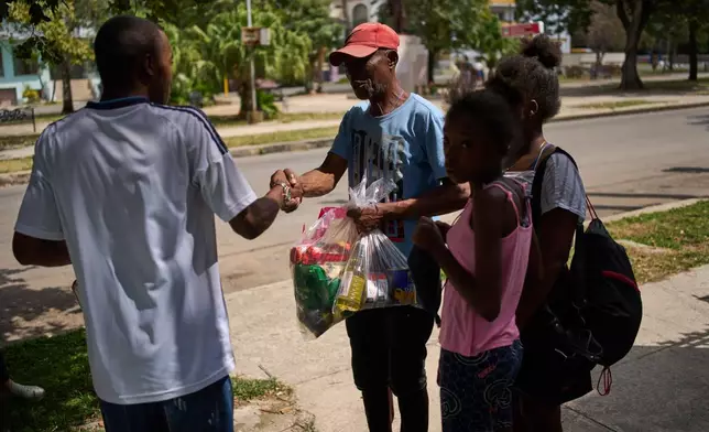 State-run bodega worker Roberto Román, left, shakes hands with Guillermo Beltran, after Beltran received bags of Mexican humanitarian assistance, in Havana, Cuba, Thursday, Feb. 19, 2026. (AP Photo/Ramon Espinosa)