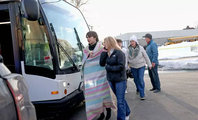 High school hockey students walk onto a public transit bus near the Lynch Arena in Pawtucket, R.I., after a shooting at the ice rink, Monday, Feb. 16, 2026. (AP Photo/Mark Stockwell)