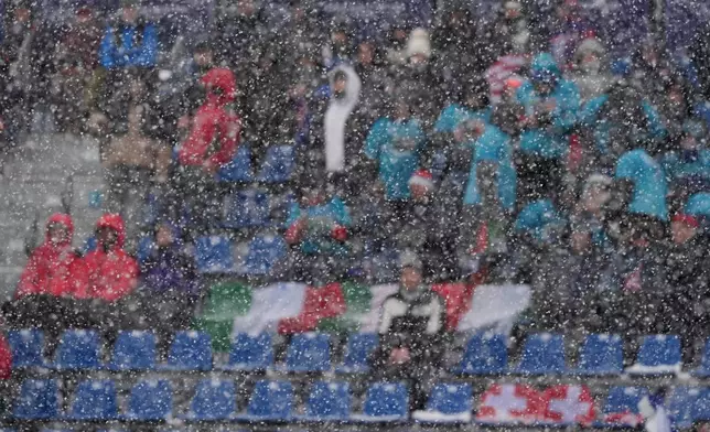 Spectators are seen through a snowfall at the finish area of an alpine ski, men's slalom race, at the 2026 Winter Olympics, in Bormio, Italy, Monday, Feb. 16, 2026. (AP Photo/Rebecca Blackwell)