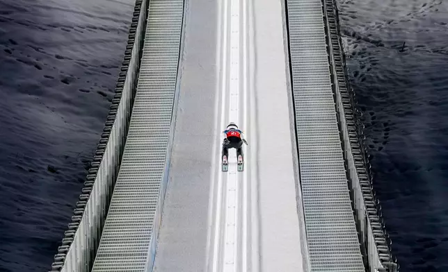 Song Qiwu, of China, goes down the ramp during his trial jump of the ski jumping men's super team competition at the 2026 Winter Olympics, in Predazzo, Italy, Monday, Feb. 16, 2026. (AP Photo/Matthias Schrader)
