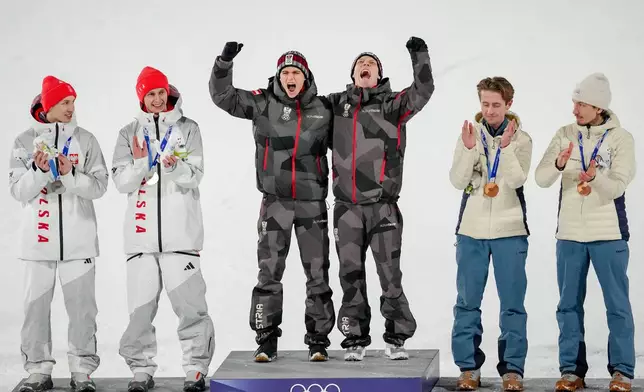Gold medalists Stephan Embacher and Jan Hoerl, of Austria, celebrate on the podium, with silver medalists Pawel Wasek and Kacper Tomasiak, of Poland, and bronze medalists Kristoffer Eriksen Sundal and Johann Andre Forfang, of Norway, after the ski jumping men's super team competition at the 2026 Winter Olympics, in Predazzo, Italy, Monday, Feb. 16, 2026. (AP Photo/Matthias Schrader)