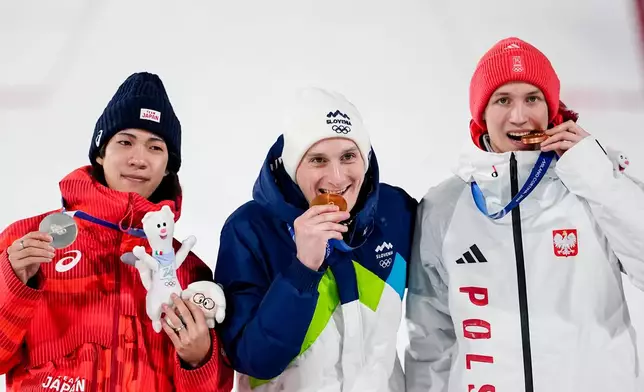 Silver medalist Ren Nikaido, of Japan, gold medalist Domen Prevc, of Slovenia, and bronze medalist Kacper Tomasiak, of Poland, pose on the podium at the end of the ski jumping men's large hill individual at the 2026 Winter Olympics, in Predazzo, Italy, Saturday, Feb. 14, 2026.. (AP Photo/Matthias Schrader)