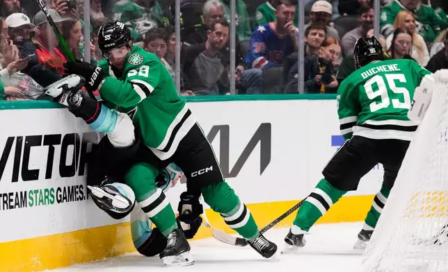 Seattle Kraken center Berkly Catton, left, is slammed against the boards by Dallas Stars' Thomas Harley (55) as Matt Duchene (95) skates past in the second period of an NHL hockey game in Dallas, Wednesday, Feb. 25, 2026. (AP Photo/Tony Gutierrez)