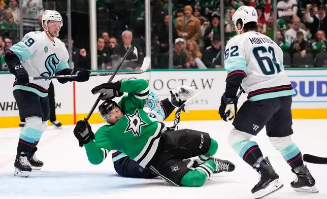 Dallas Stars left wing Jason Robertson falls backwards over Seattle Kraken goaltender Joey Daccord, center rear, as Vince Dunn (29) and Brandon Montour (62) help defend the net in the first period of an NHL hockey game in Dallas, Wednesday, Feb. 25, 2026. (AP Photo/Tony Gutierrez)