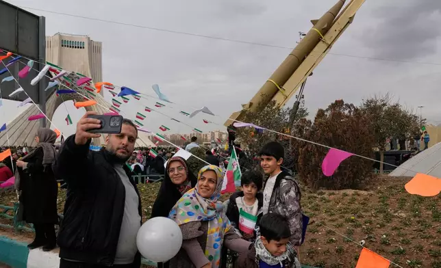 People take a selfie in front of an Iranian-built missile during an annual rally marking 1979 Islamic Revolution at the Azadi (Freedom) sq. in Tehran, Iran, Wednesday, Feb. 11, 2026. (AP Photo/Vahid Salemi)