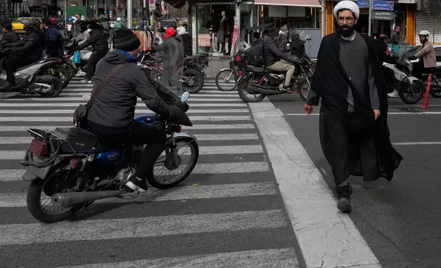 A cleric crosses an intersection in downtown Tehran, Iran, Monday, Feb. 9, 2026. (AP Photo/Vahid Salemi)