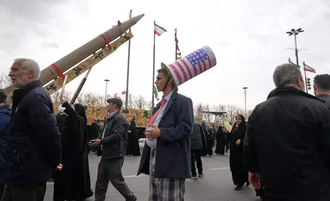 A man wears a Uncle Sam's hat as he stands in front of an Iranian-built missile during an annual rally marking 1979 Islamic Revolution at the Azadi (Freedom) sq. in Tehran, Iran, Wednesday, Feb. 11, 2026. (AP Photo/Vahid Salemi)